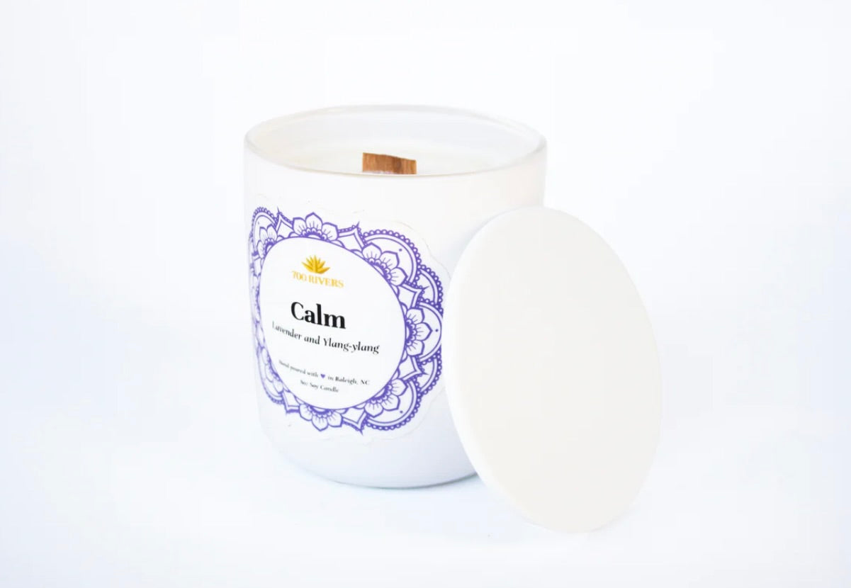 White candle with a wooden wick labeled 'Calm' with blue floral designs