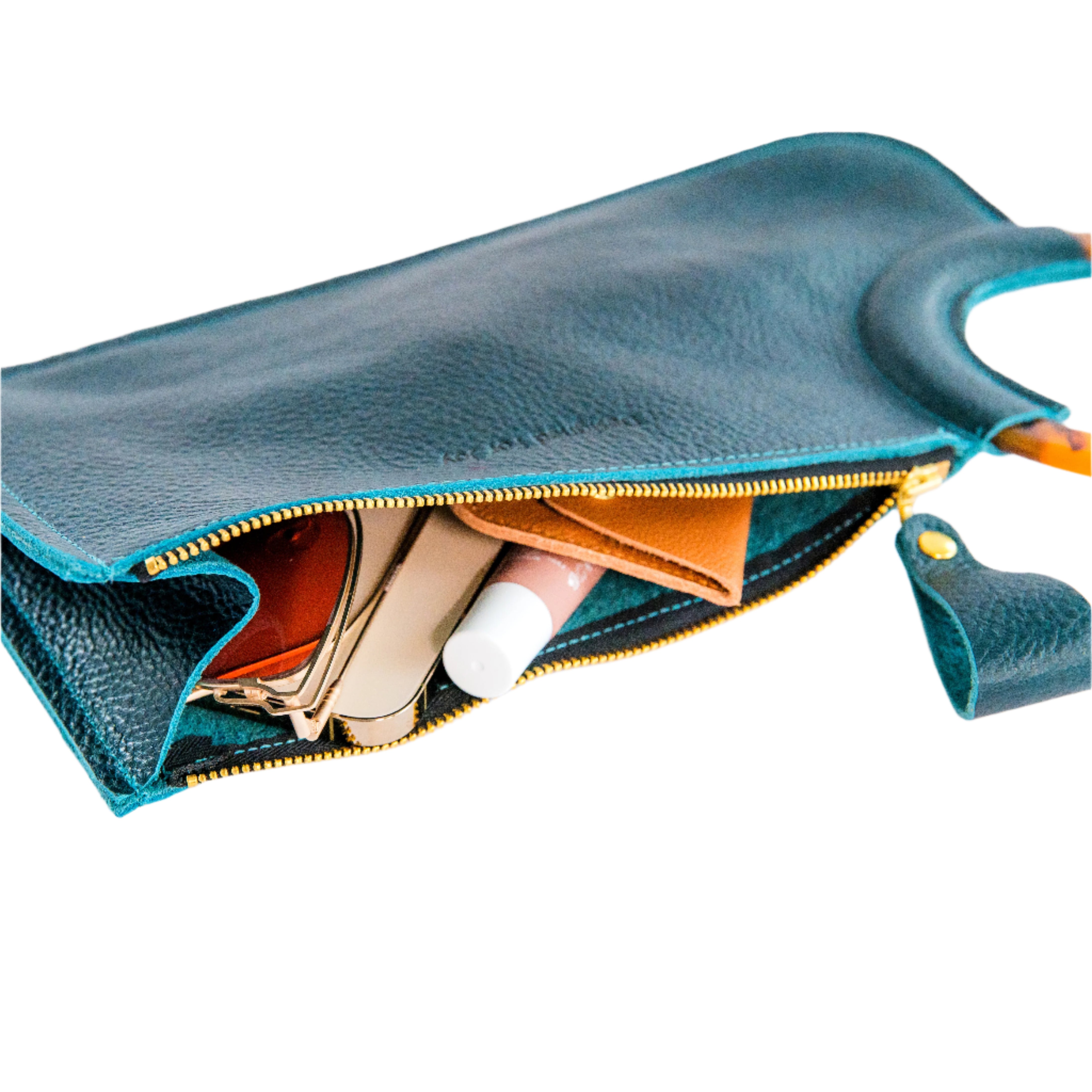 Items like lip balm peeking out of an opened teal wristlet handbag on a white background