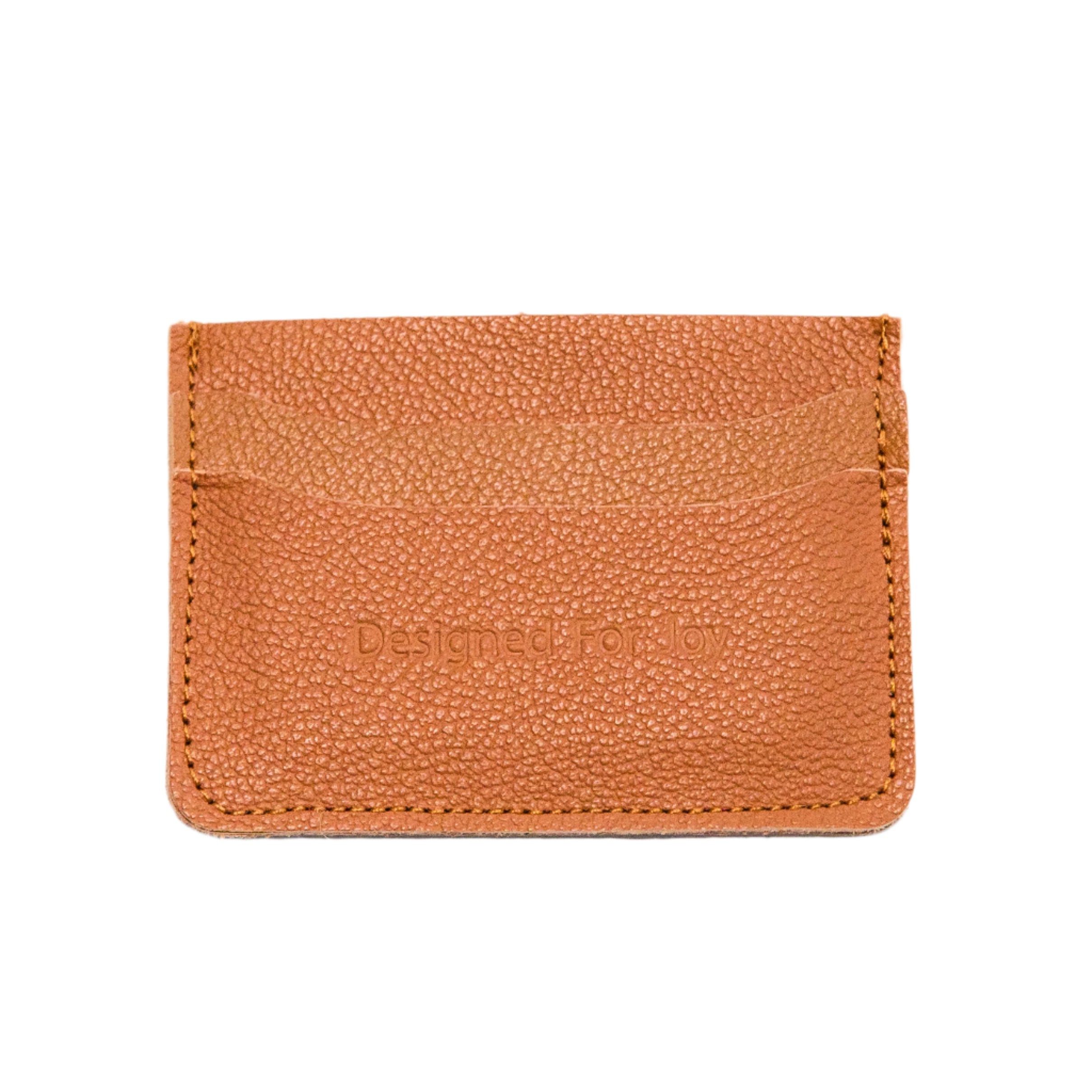 Carmel brown leather credit card wallet with 'Designed for Joy' text, on a white background
