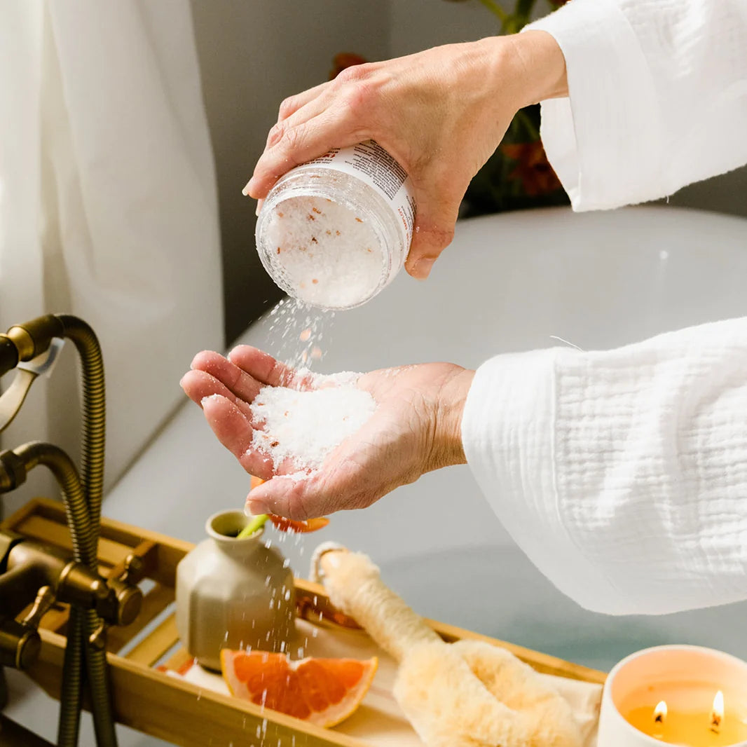 Close-up of a person pouring bath salt into their hand above a bath tub