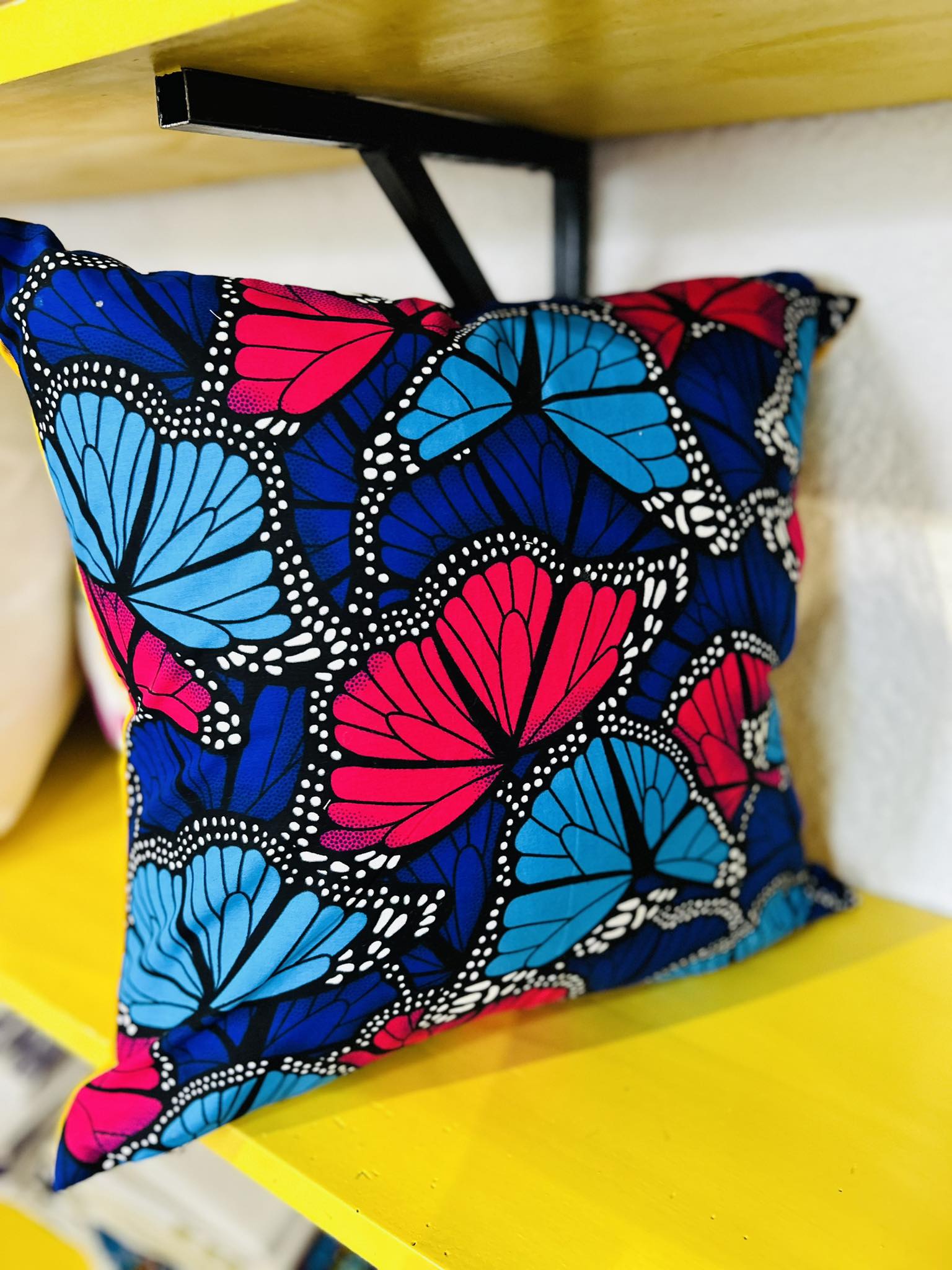 Decorative pillow with blue, dark blue, and red colored butterflies