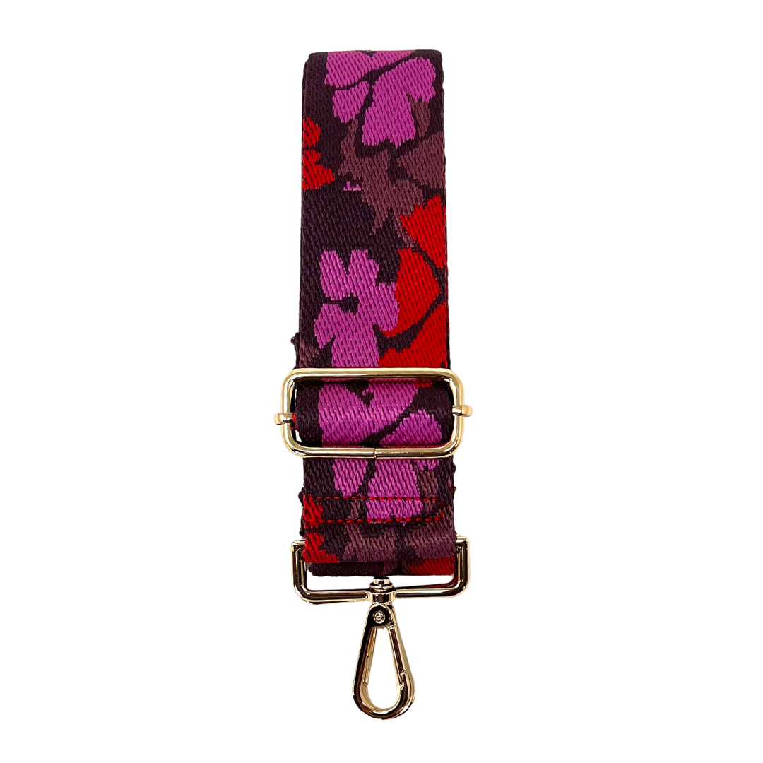 A red and purple floral-patterned crossbody strap with goldtone hardware, displayed on a white background
