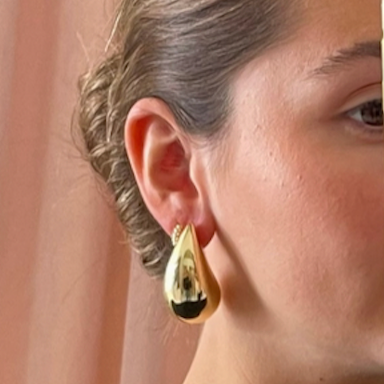Person wearing a gold puffy teardrop earring