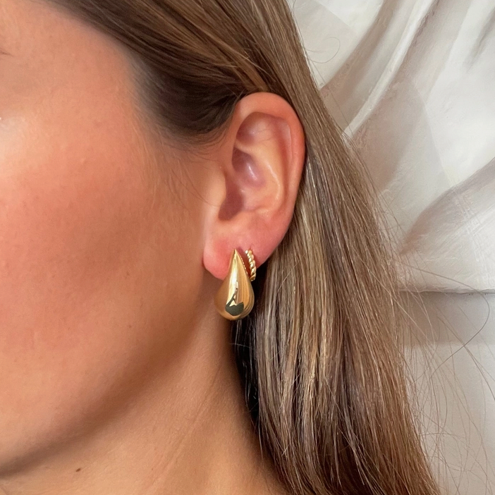 Person wearing a gold puffy teardrop earring