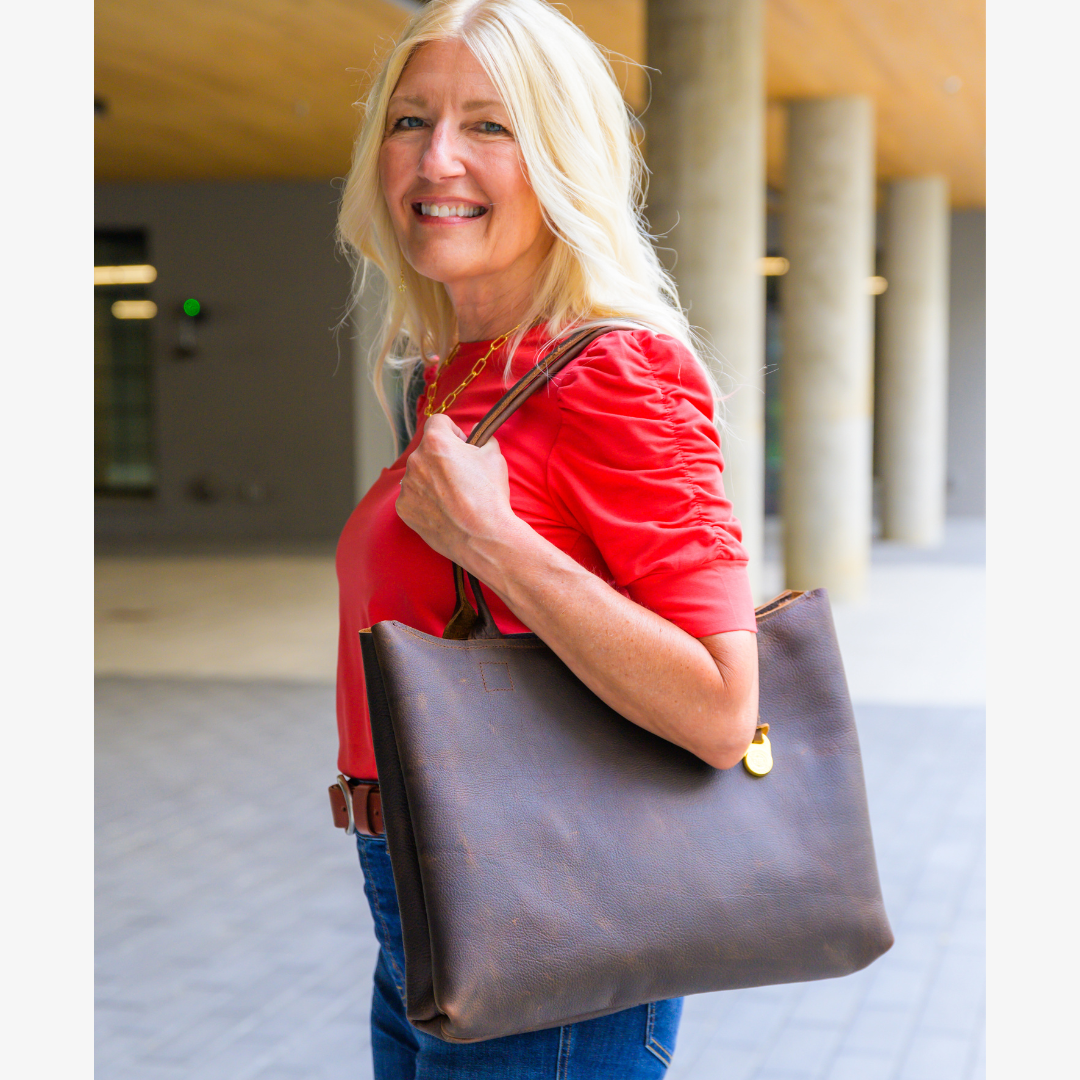 A person carrying a brown laptop tote bag while in an outdoor setting