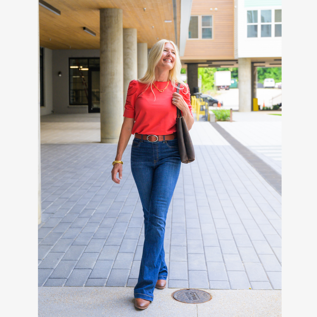 A person walking while wearing a brown laptop tote bag in an outdoor setting