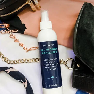 A white spray bottle labeled 'Solemates All Weather Protector' displayed on a background of bag chains