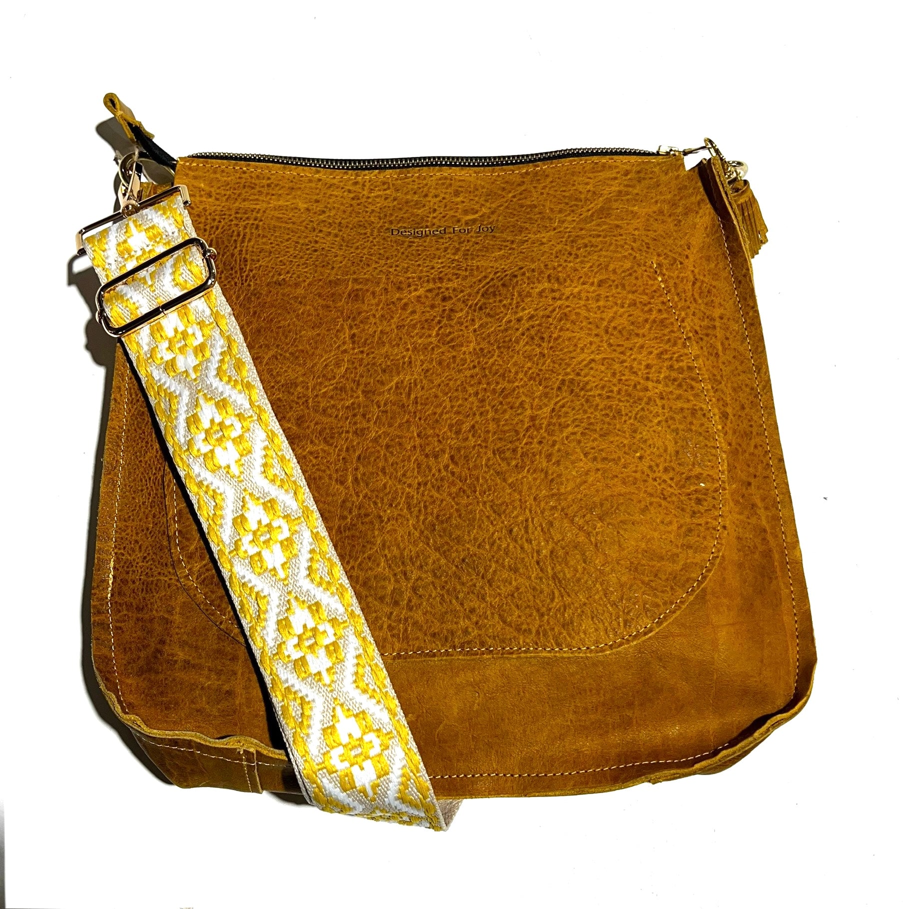 Gold-brown leather bag with a yellow tapestry strap on a white background