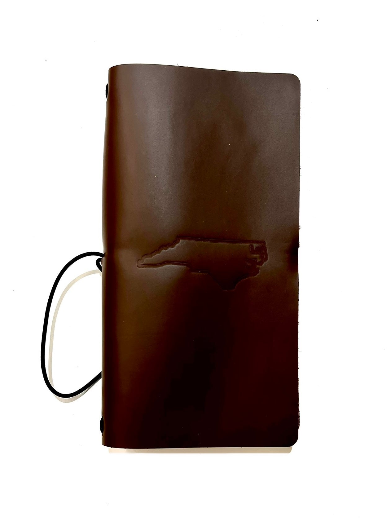 Brown traveler journal with an NC outline stamped on the cover and black strap, displayed on a white background