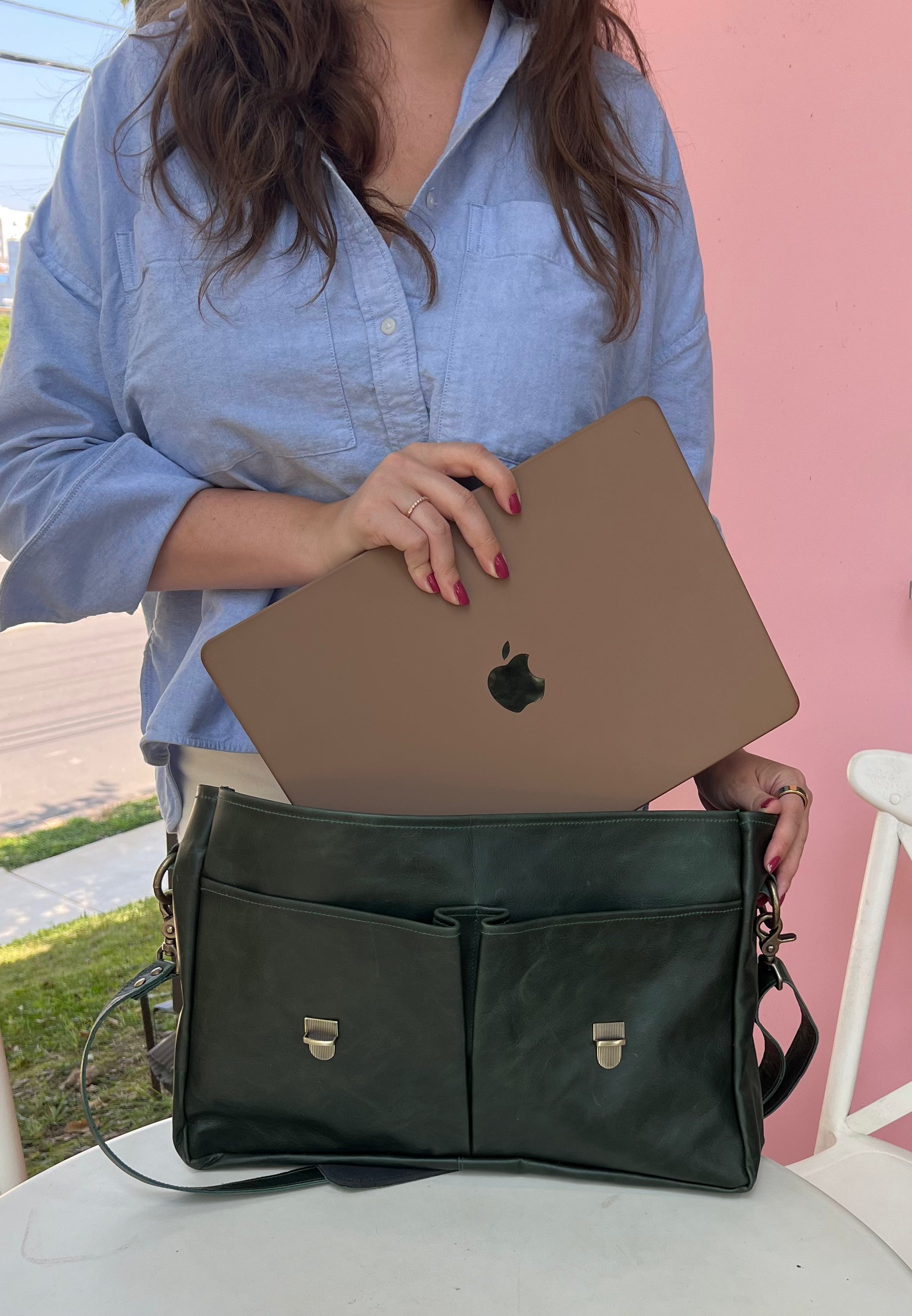 Person putting a laptop into a dark green professional messenger/laptop bag