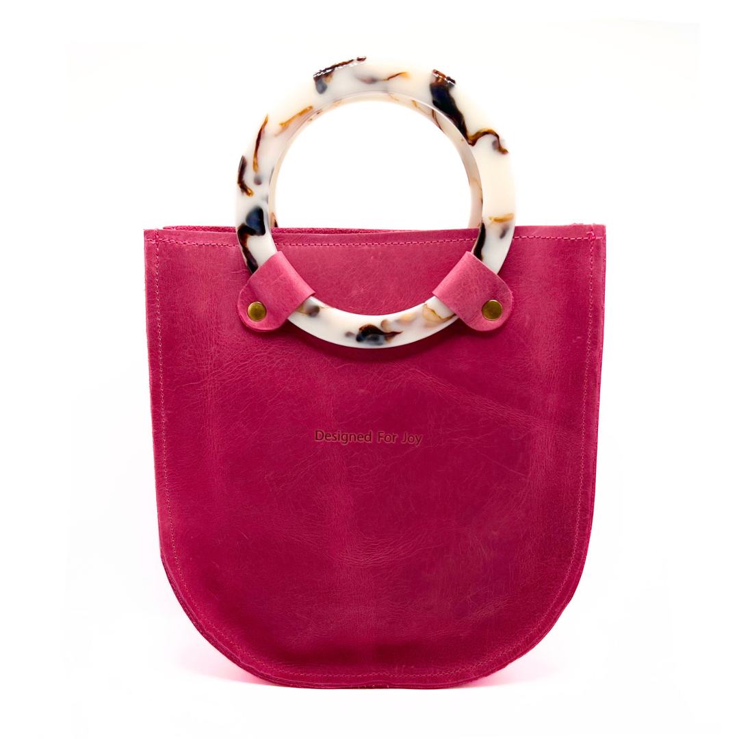 Raspberry pink top handle handbag with two resin handles and a smooth leather finish, displayed on a white background