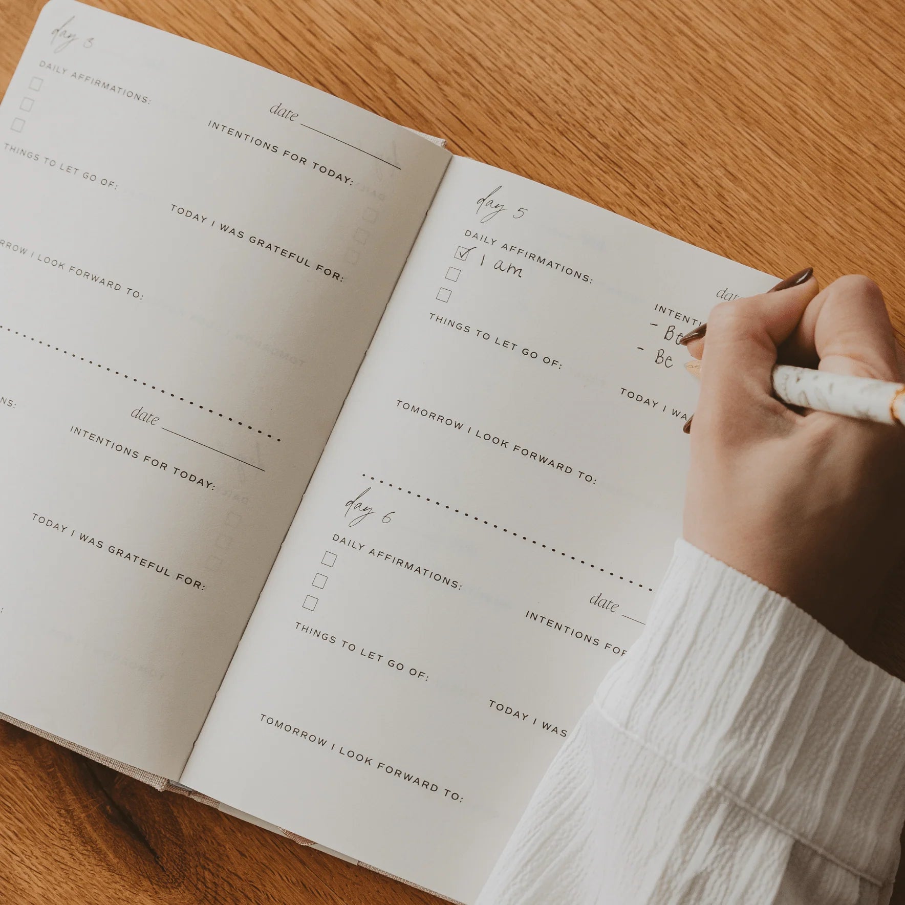 Person writing in a gratitude journal on a wooden table