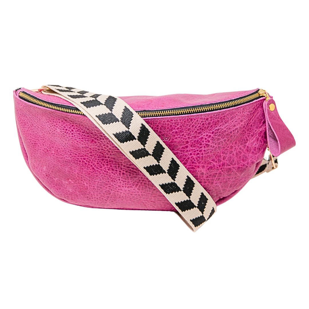 Pink crossbody sling handbag with a black and white geometric patterned strap on a white background