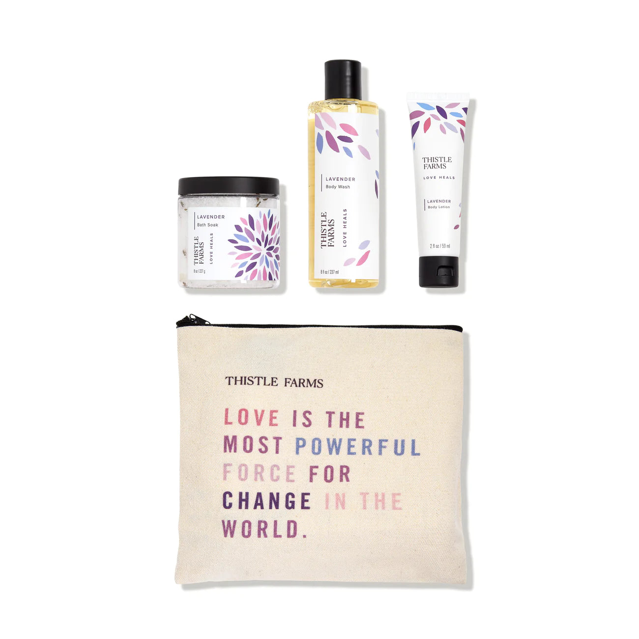A gift set from Thistle Farms, including a jar of bath soak, a bottle of body wash, and a tube of body lotion, arranged with a reusable canvas travel pouch that has a quote printed on it