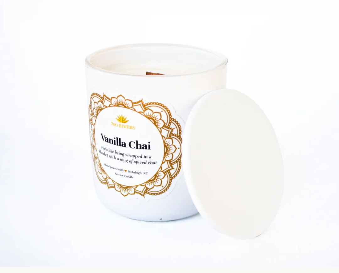 White candle with a wooden wick labeled 'Vanilla Chai' with brown floral designs