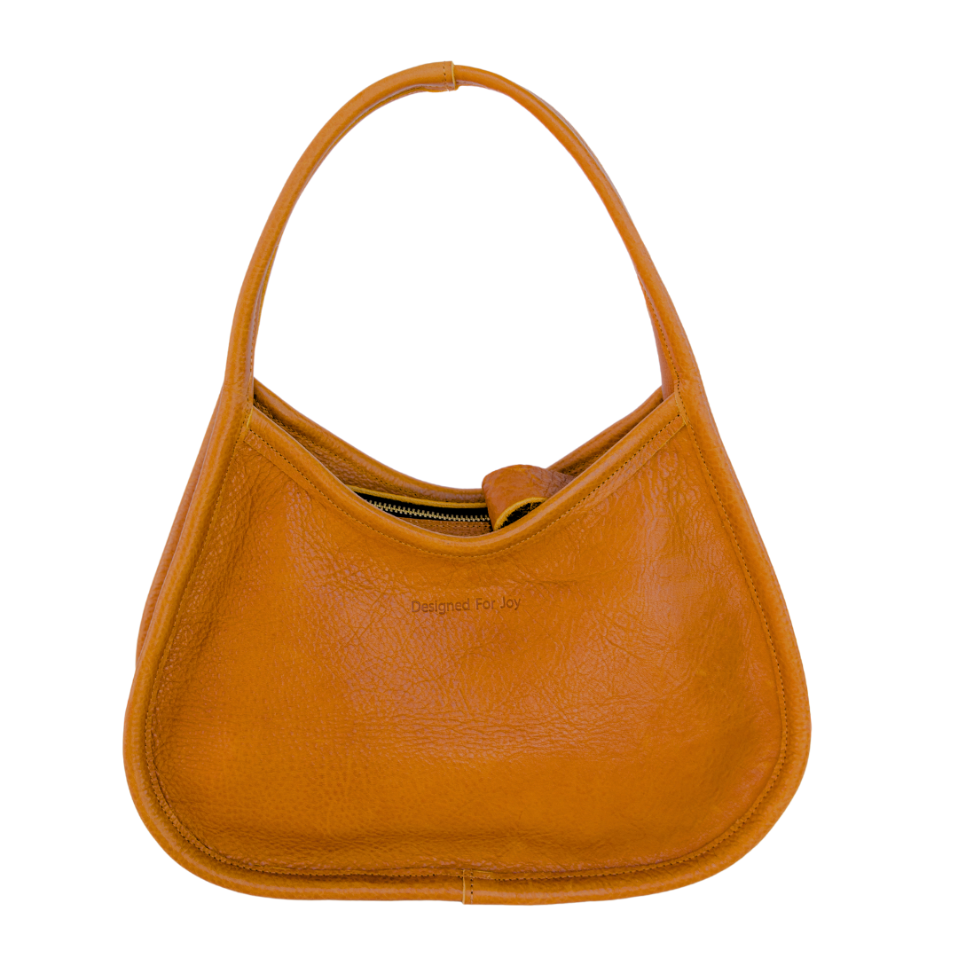 Caramel brown leather shoulder handbag with a wide base and narrow handles displayed on a white background