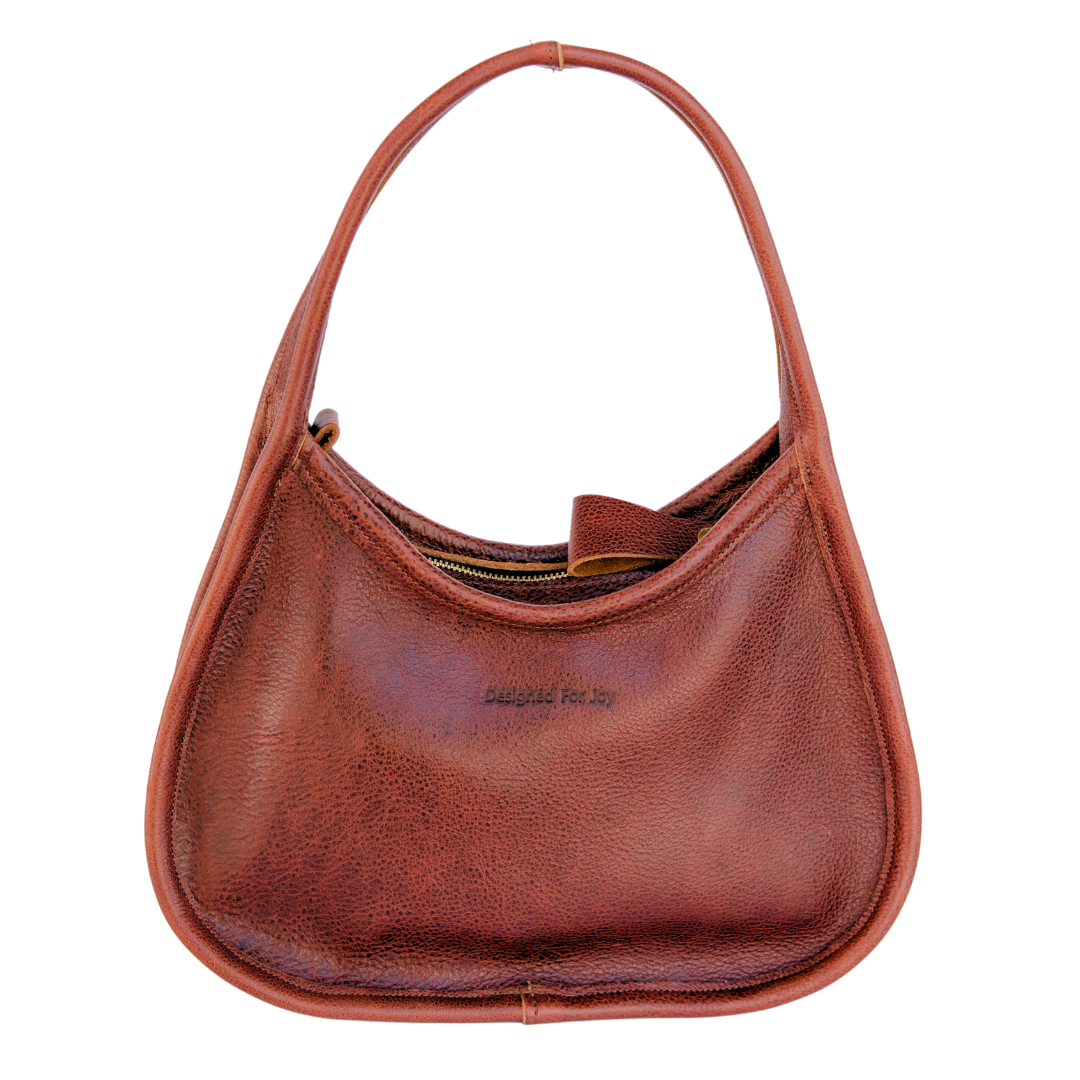 Cinnamon brown leather shoulder handbag with a wide base and narrow handles displayed on a white background