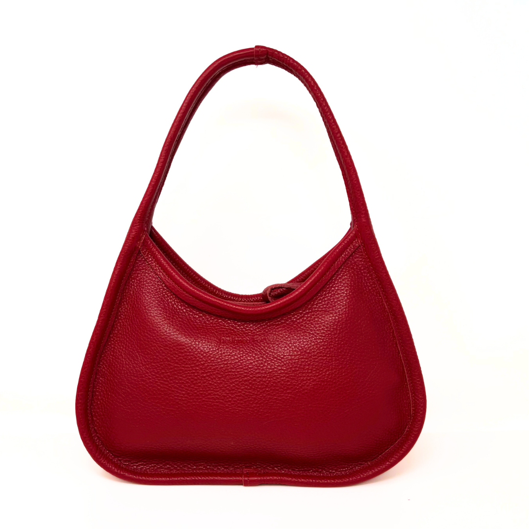 Red leather shoulder handbag with a wide base and narrow handles displayed on a white background