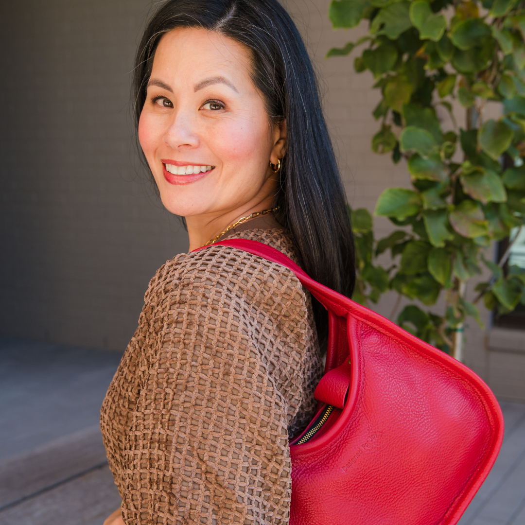 Side angle of a person wearing a red shoulder handbag in an outdoor setting