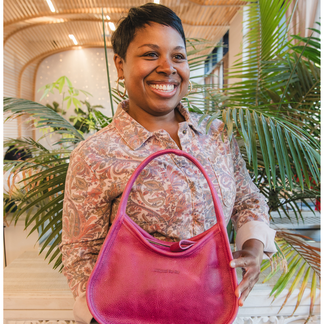 Person carrying a pink shoulder handbag in an indoor setting with plants behind them