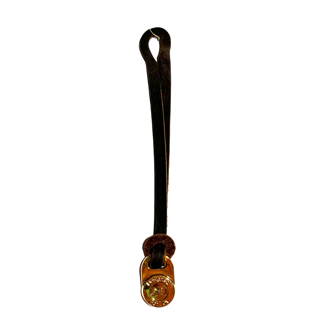 Dark brown leather bag charm with a gold-tone medallion on a white background