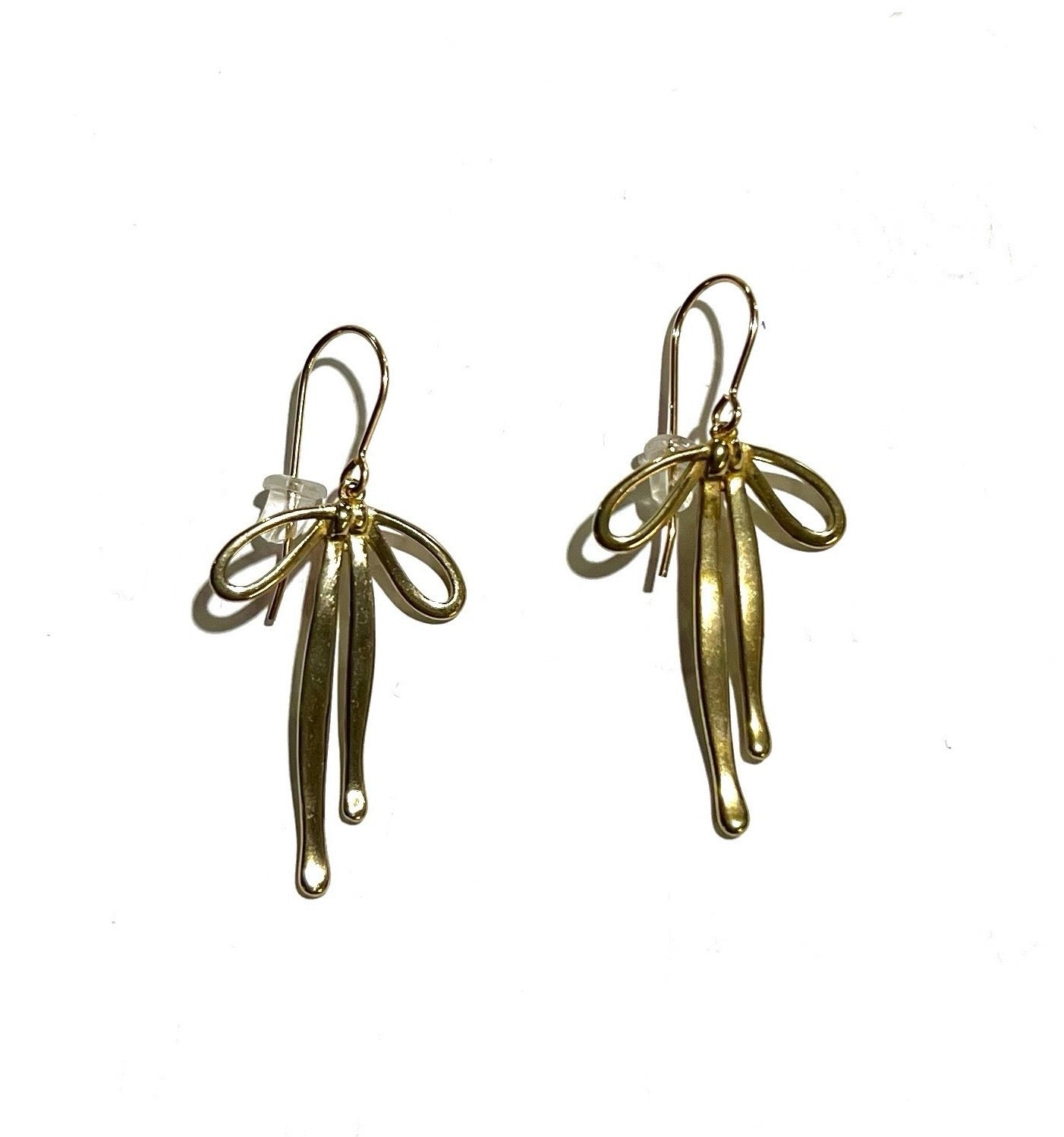 Pair of gold-colored dangly bow earrings on a white background