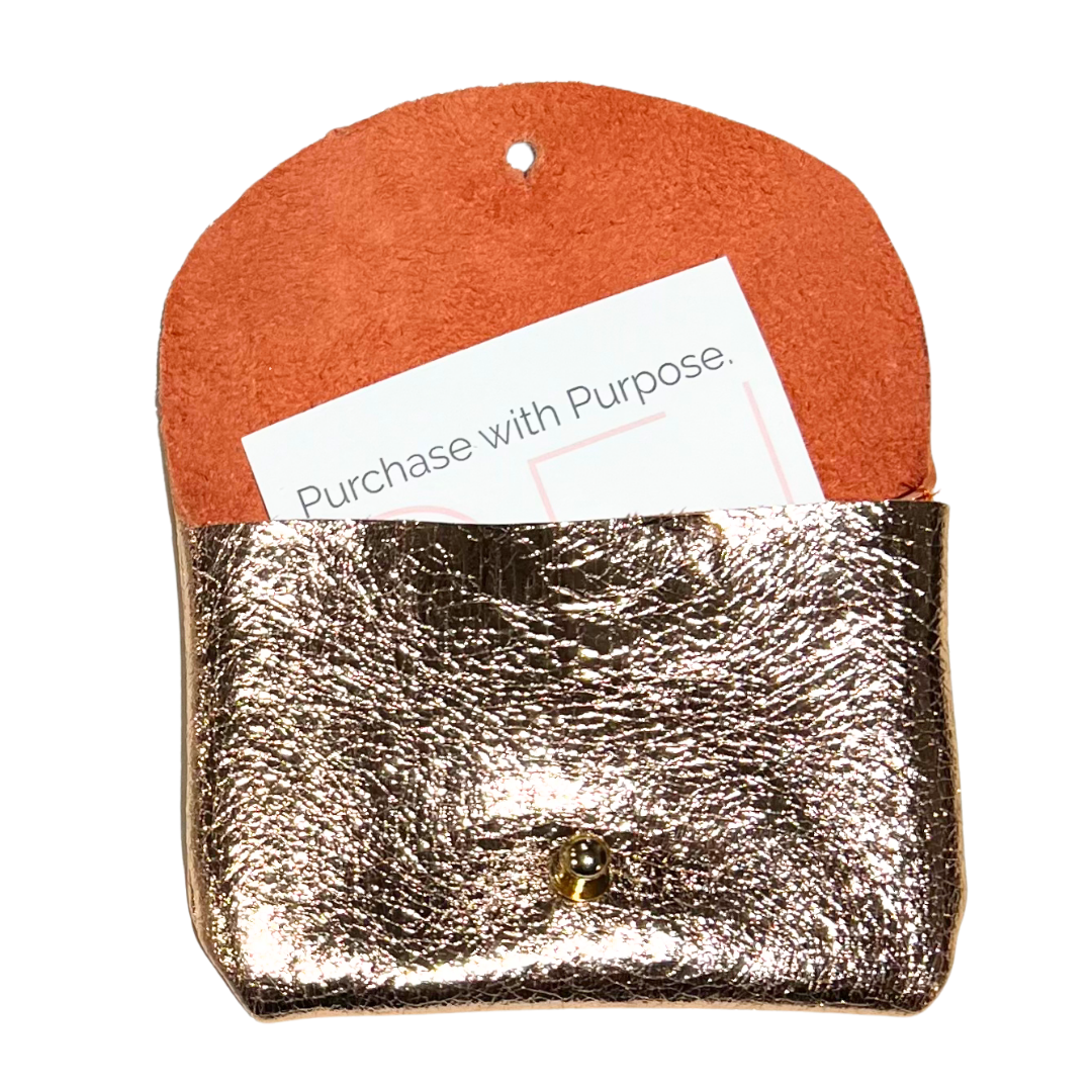Open gold metallic button stud coin purse with a paper labeled, 'Purchase with Purpose.' sticking out of it