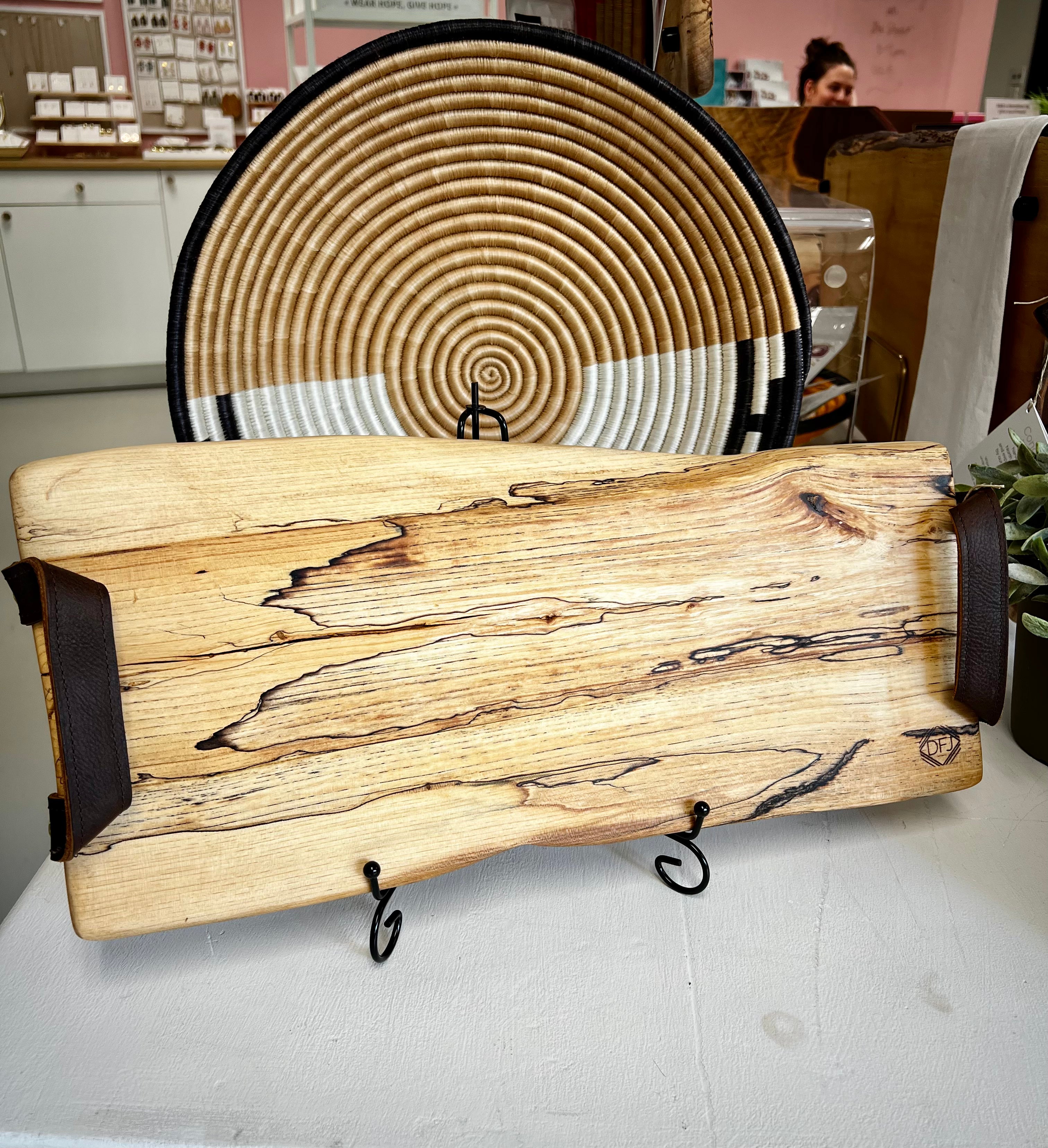 A live-edge maple wood charcuterie board displayed on a table with a decorative bowl behind it