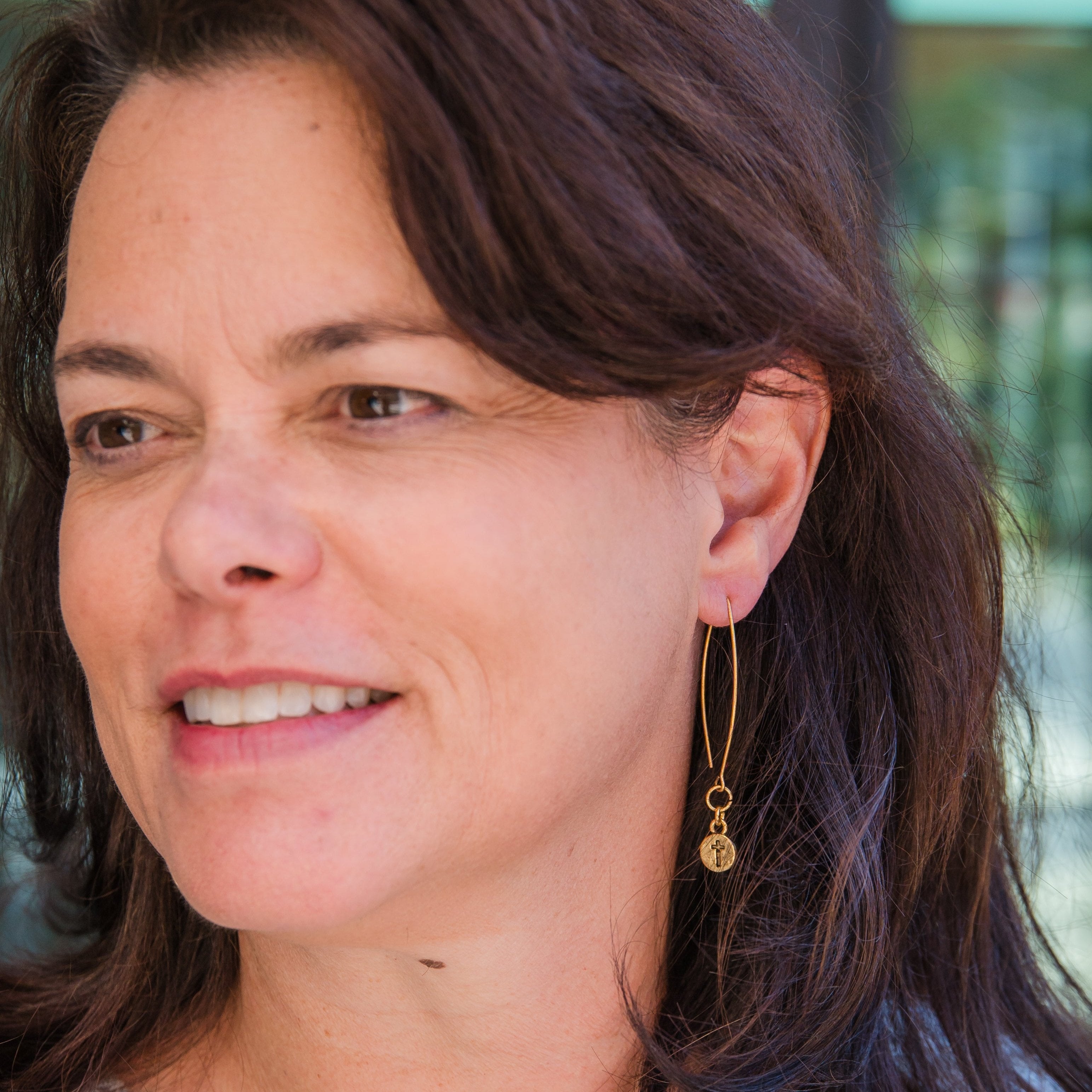 A close-up of a person wearing a gold cross earring