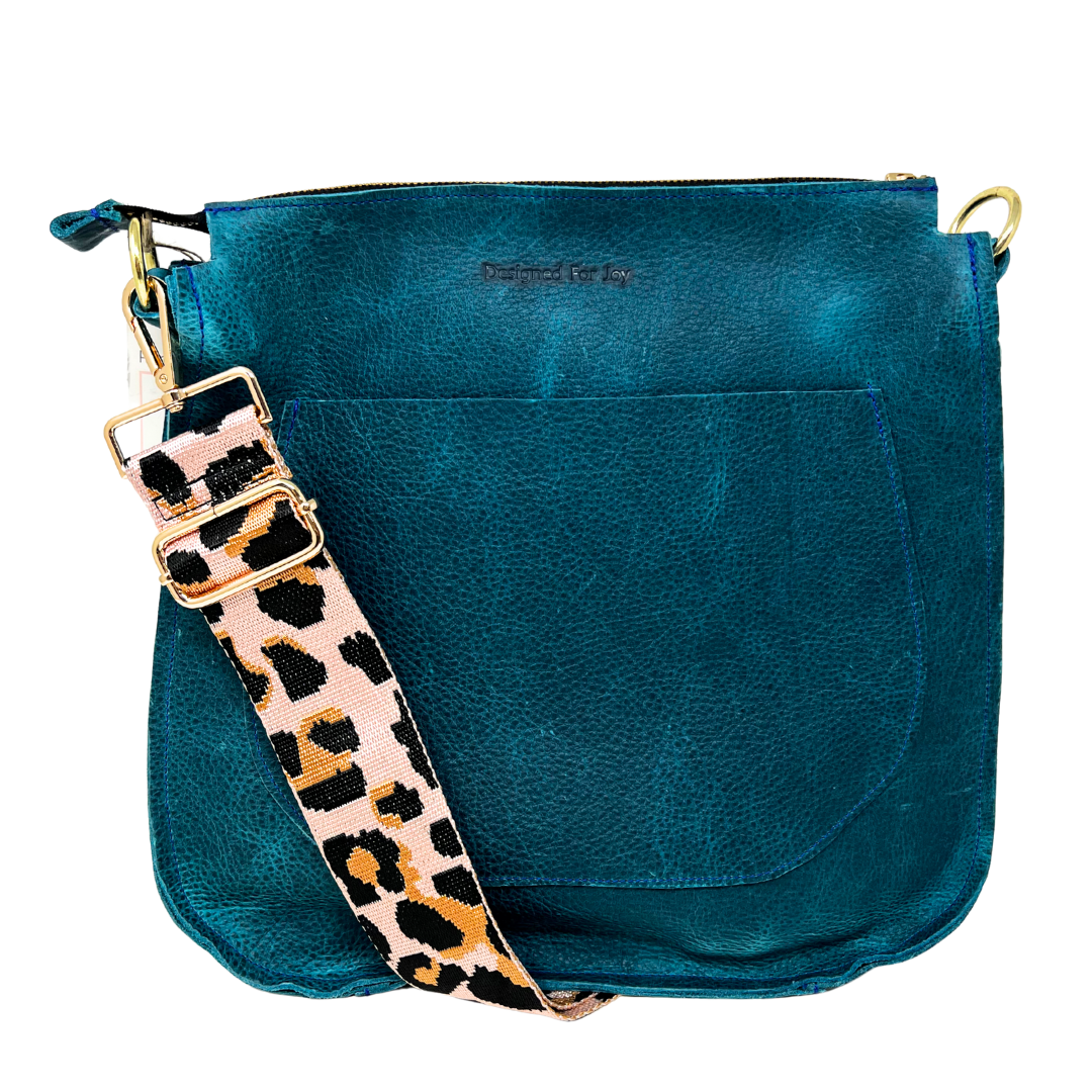 Blue leather bag with a pink leopard print strap on a white background