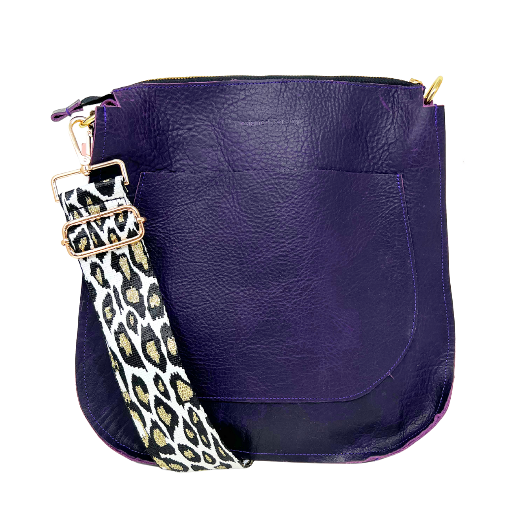 Purple leather bag with a black and gold cheetah print strap on a white background