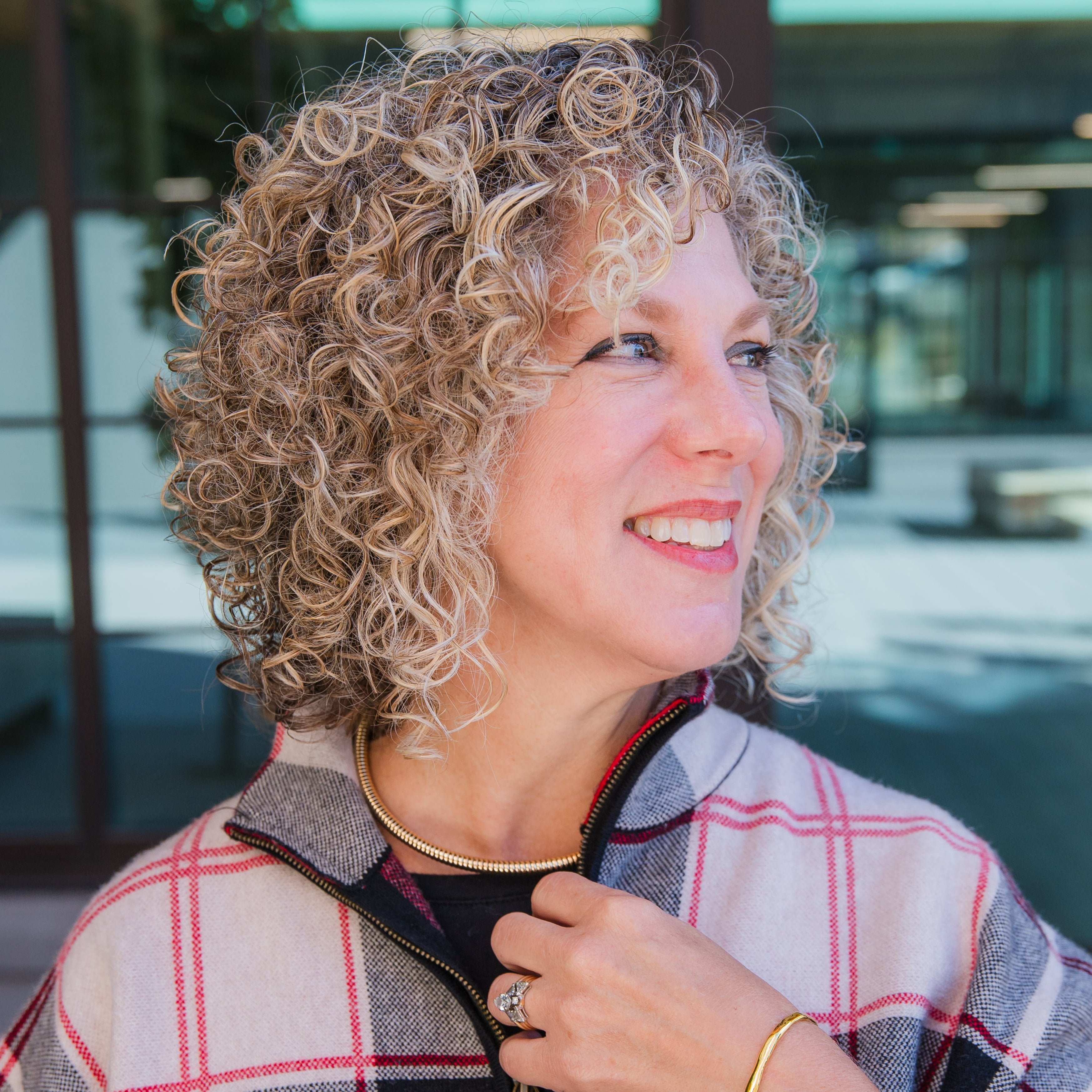 Headshot of a woman wearing the gold coil choker necklace while looking to the side in an outdoor setting
