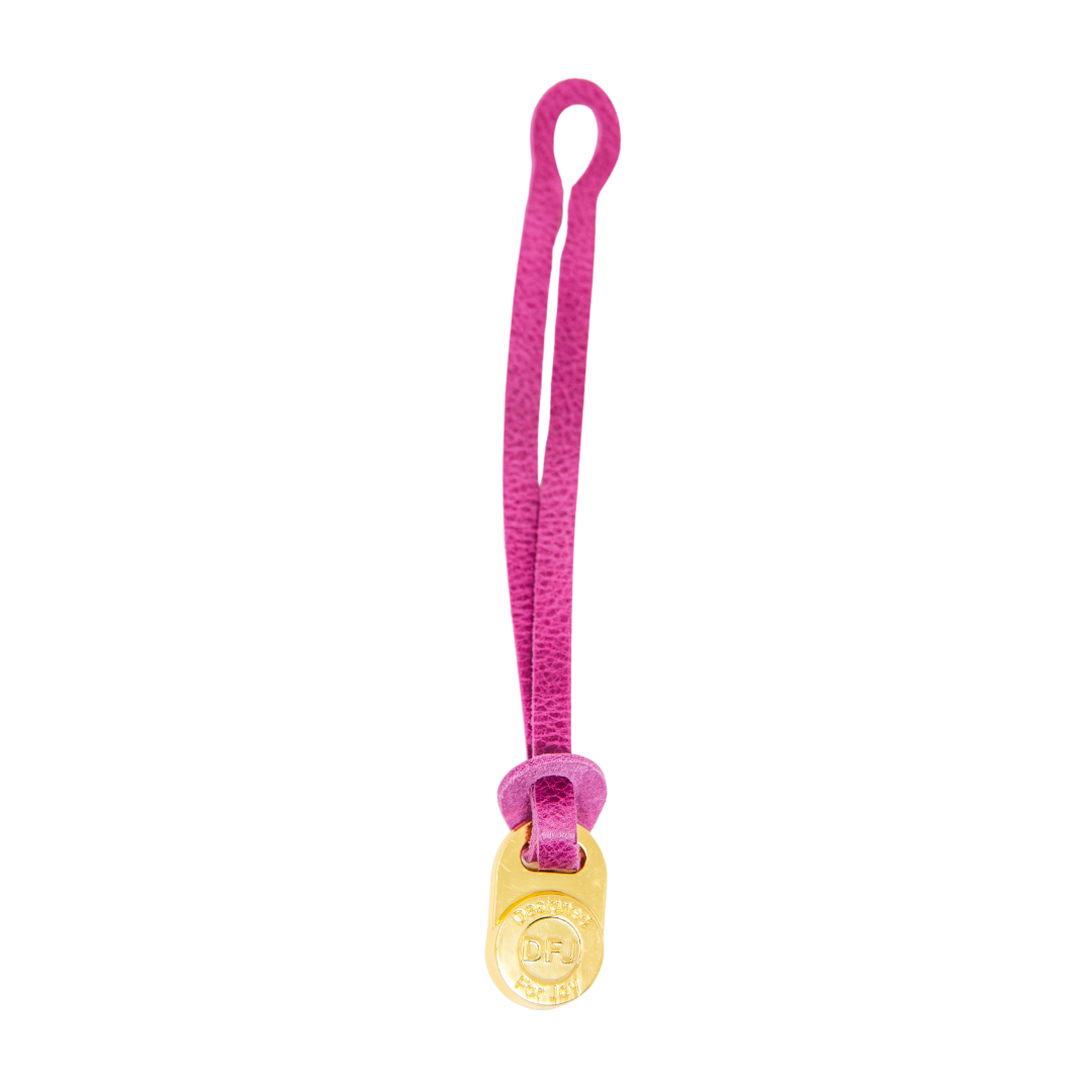 Pink leather bag charm with a gold-tone medallion on a white background