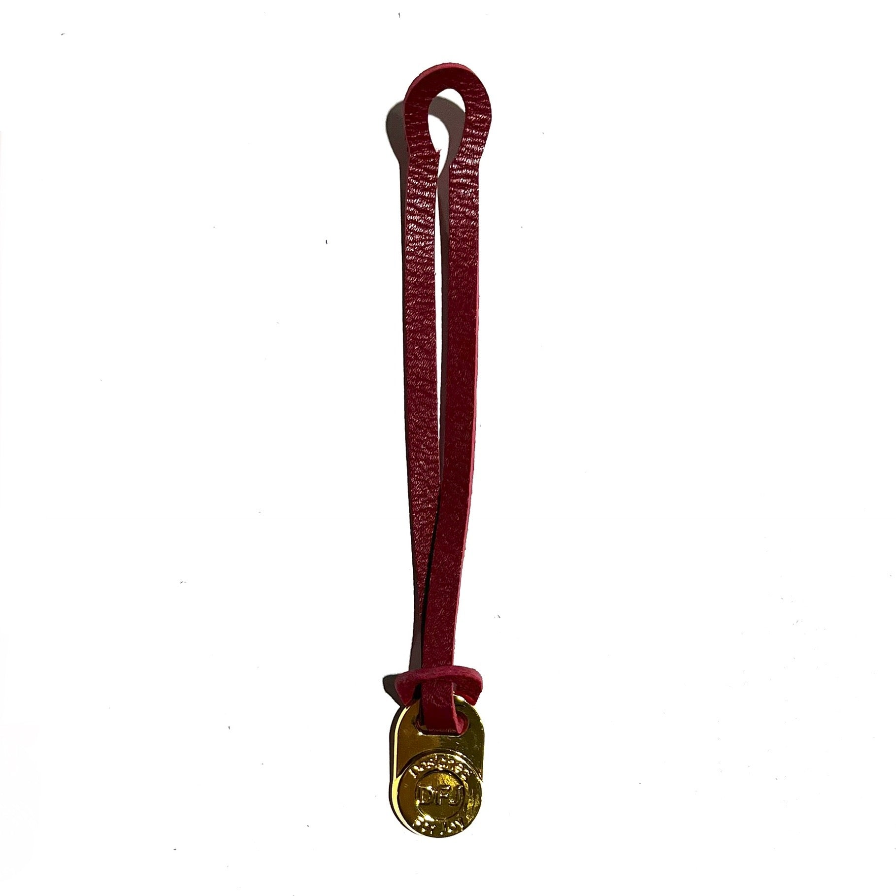 Red leather bag charm with a gold-tone medallion on a white background