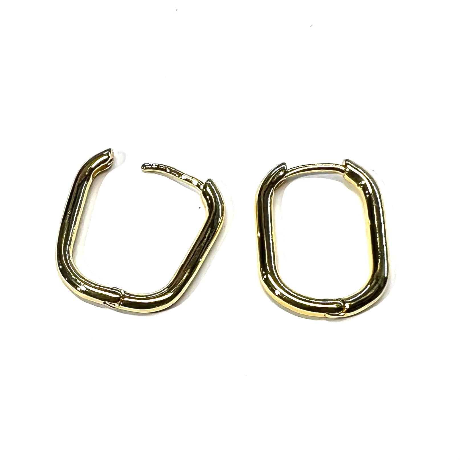 A pair of gold-colored oval huggie hoop earrings on a white background
