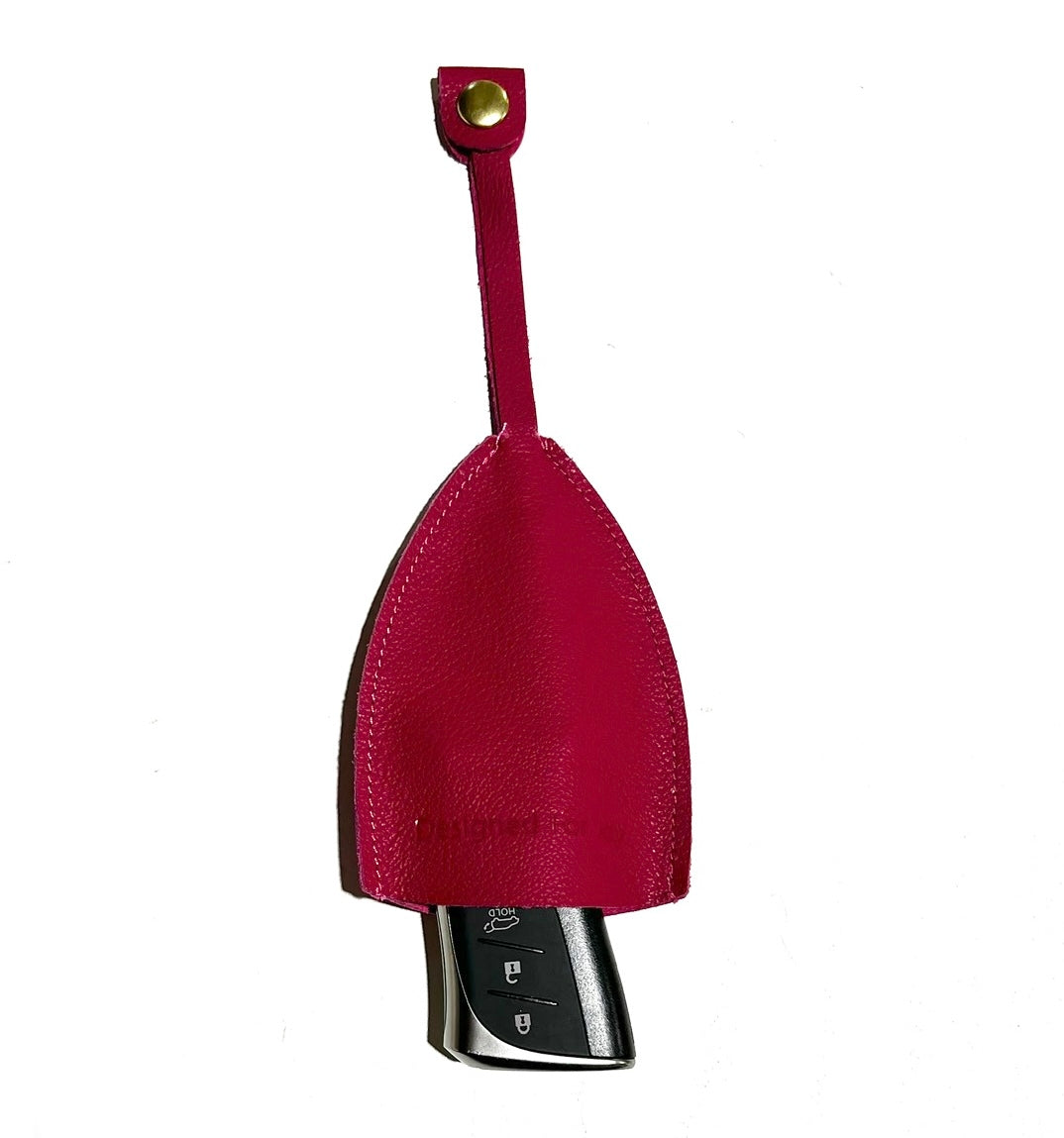 Pink leather car key cover with a car key sticking out of it on a white background
