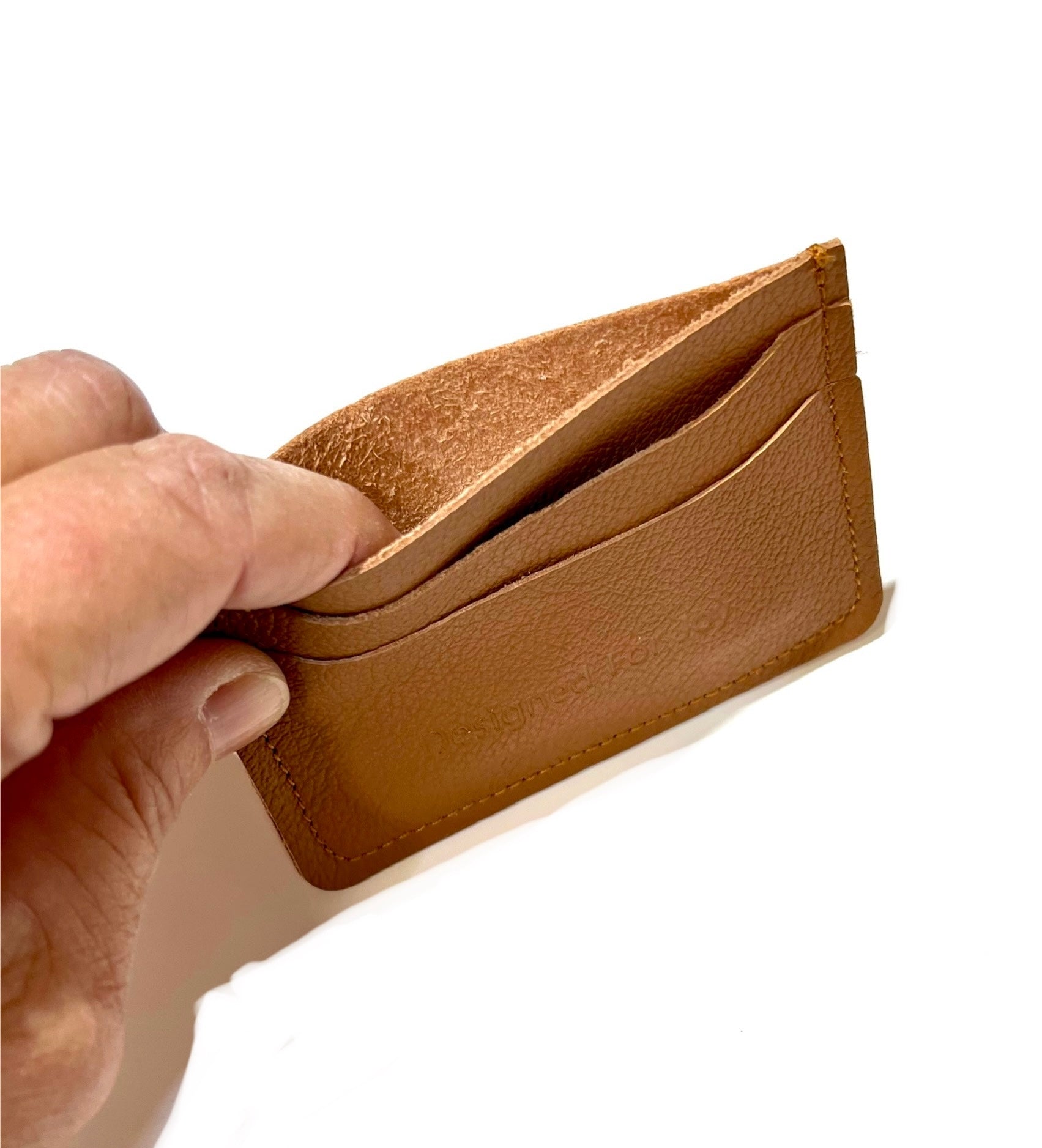 Caramel brown leather credit card wallet being opened up by a hand