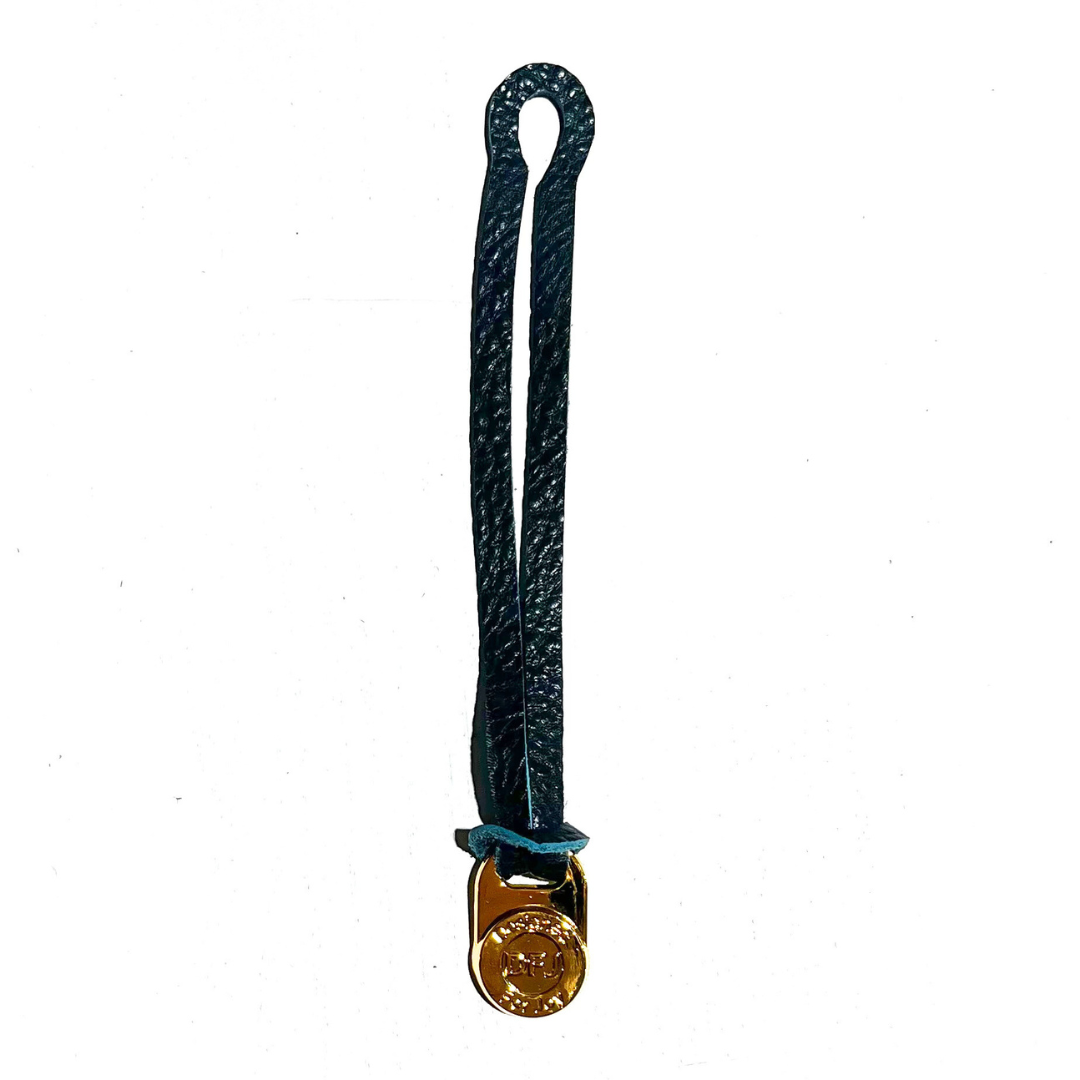 Teal leather bag charm with a gold-tone medallion on a white background