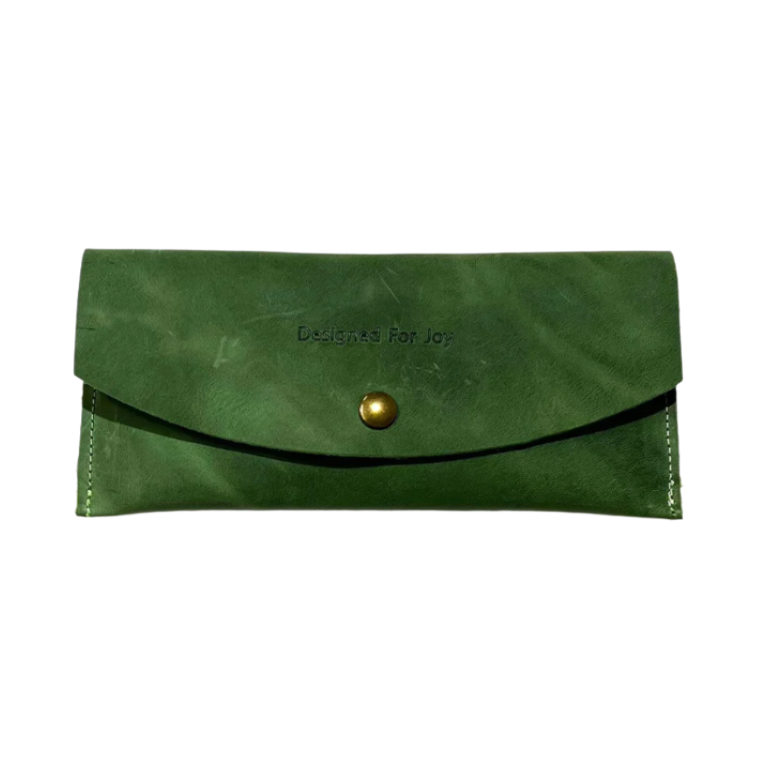 Evergreen leather penny wallet with snap closure and 'Designed for Joy' text, displayed on a white background