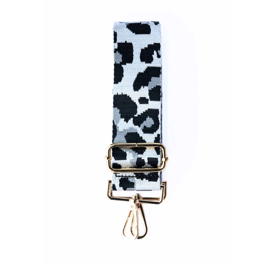 White, gray, and black adjustable crossbody strap with a leopard pattern and metal hardware, displayed on a white background