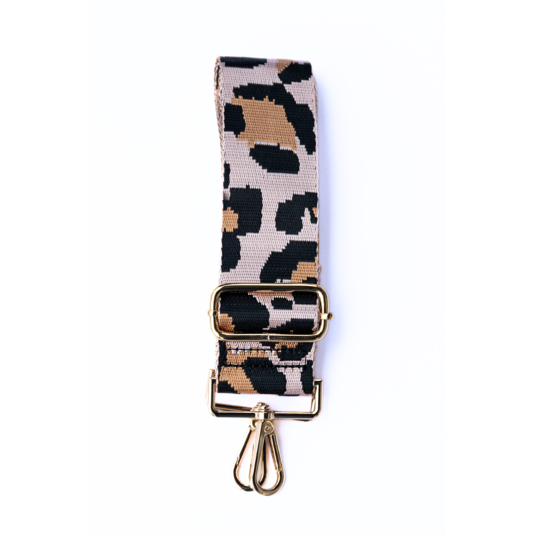 Light pink, tan, and black adjustable crossbody strap with a leopard pattern and metal hardware, displayed on a white background