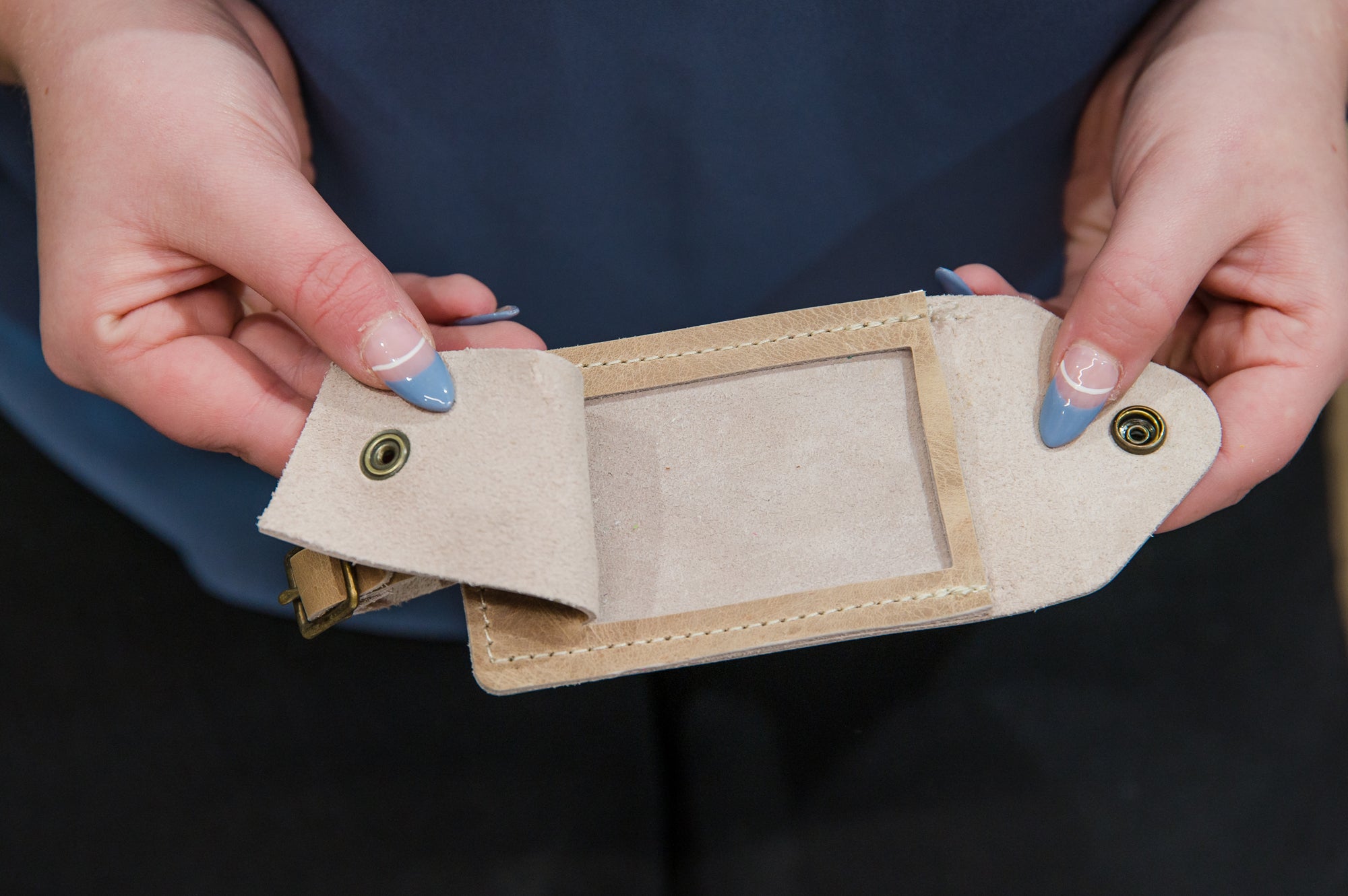 Close-up of a person holding open a tan luggage tag
