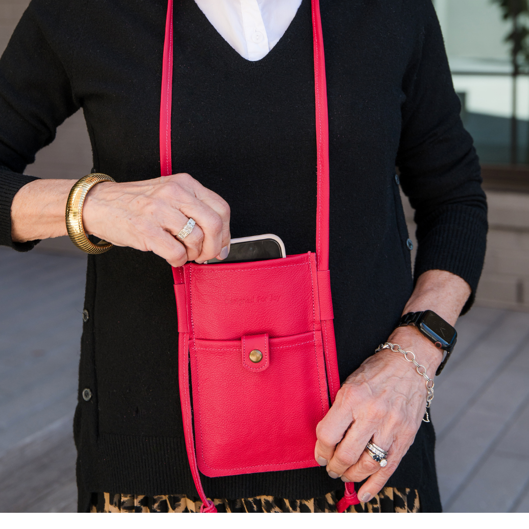 Close-up of a person wearing a pink mini crossbody handbag while pulling a phone out of it