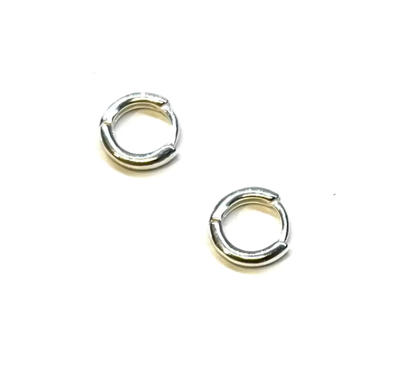 Pair of small silver huggie hoop earrings on a white background