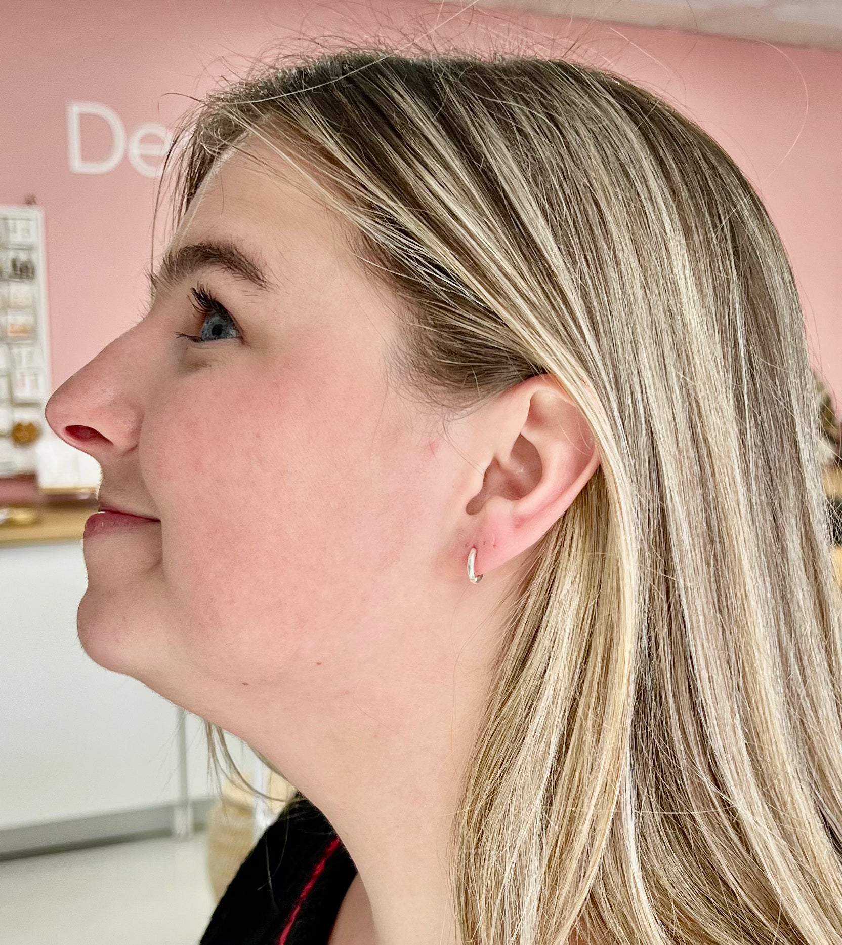Side profile of person wearing a small silver huggie hoop earring