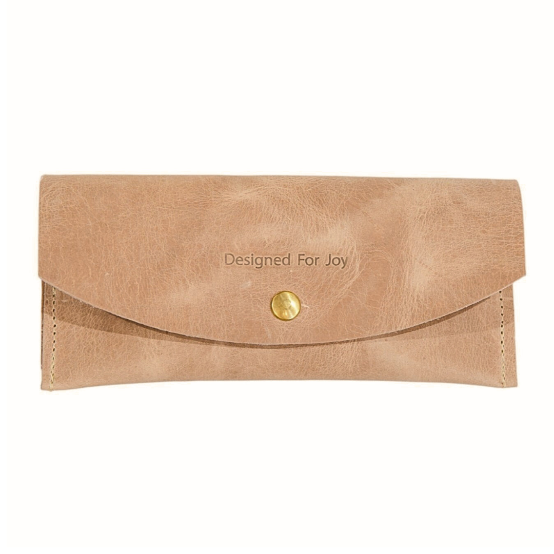 Tan leather penny wallet with snap closure and 'Designed for Joy' text, displayed on a white background