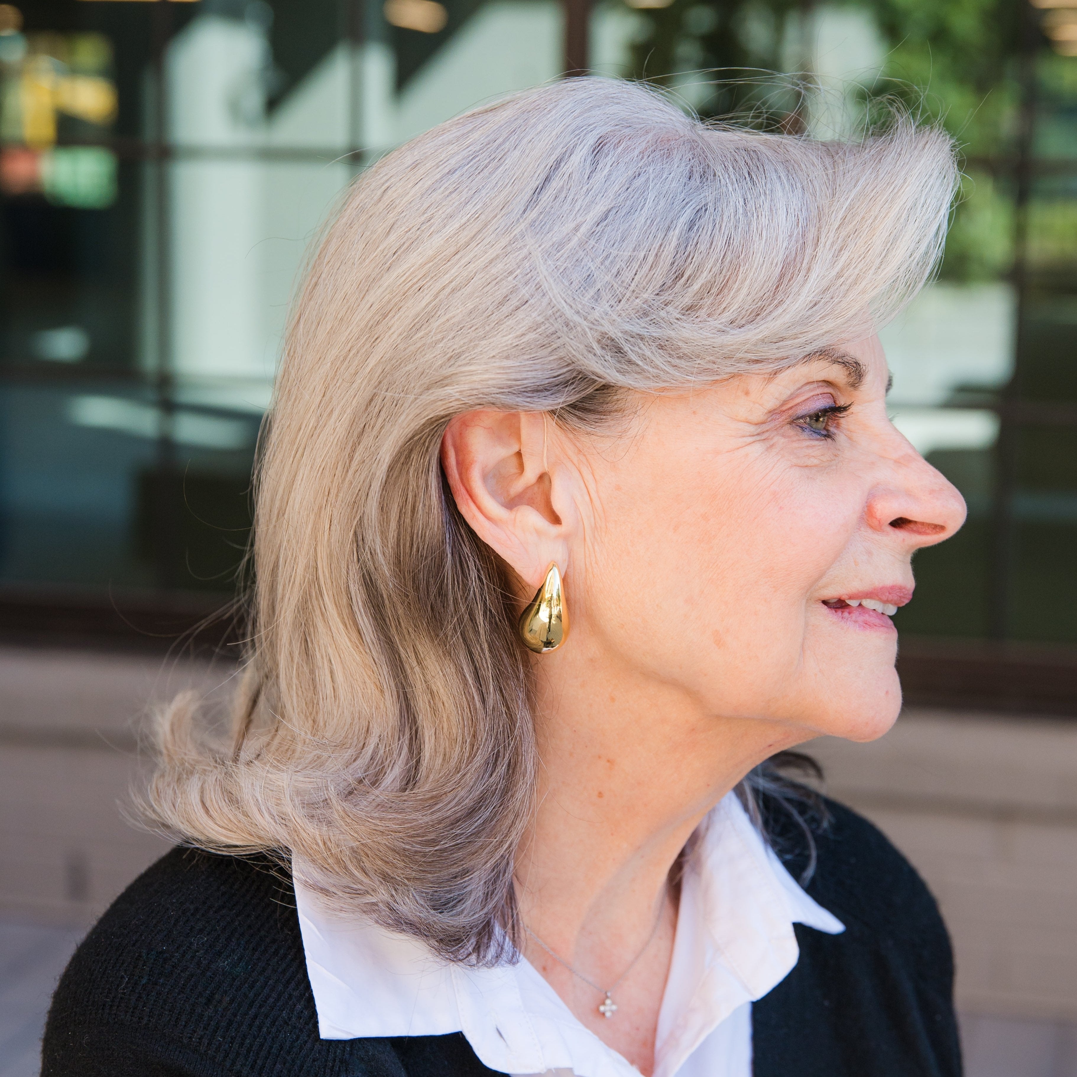 Side profile of a person wearing a gold puffy teardrop earring