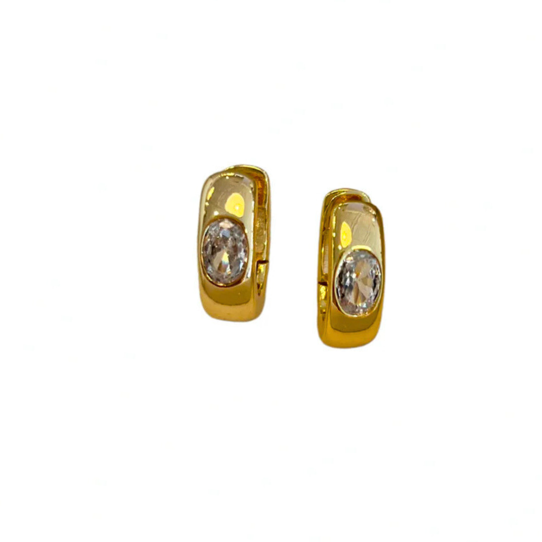 Pair of gold hoop earrings with cubic zirconia crystals on the front, on a white background
