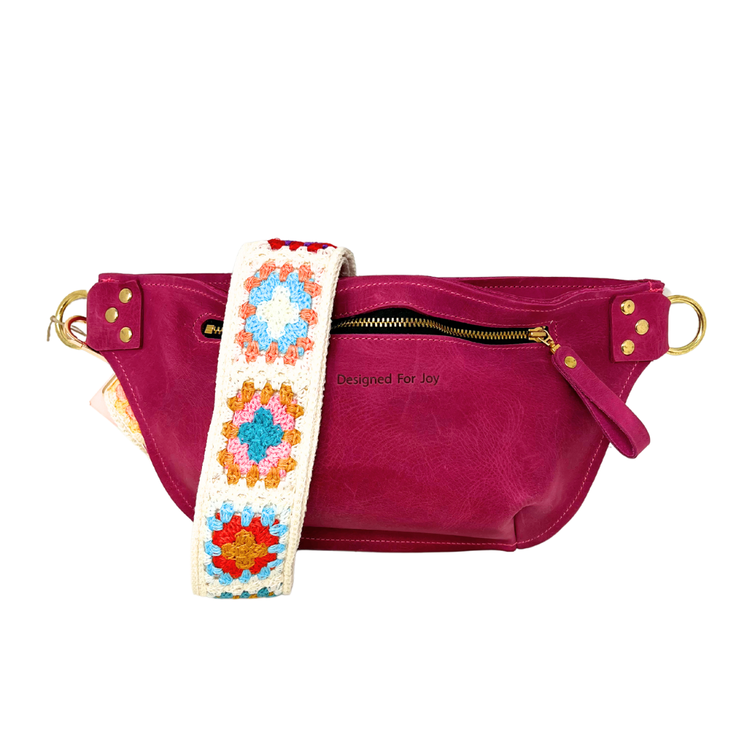 Raspberry pink leather crossbody sling bag with a multicolored crochet square strap, featuring a full zippered compartment