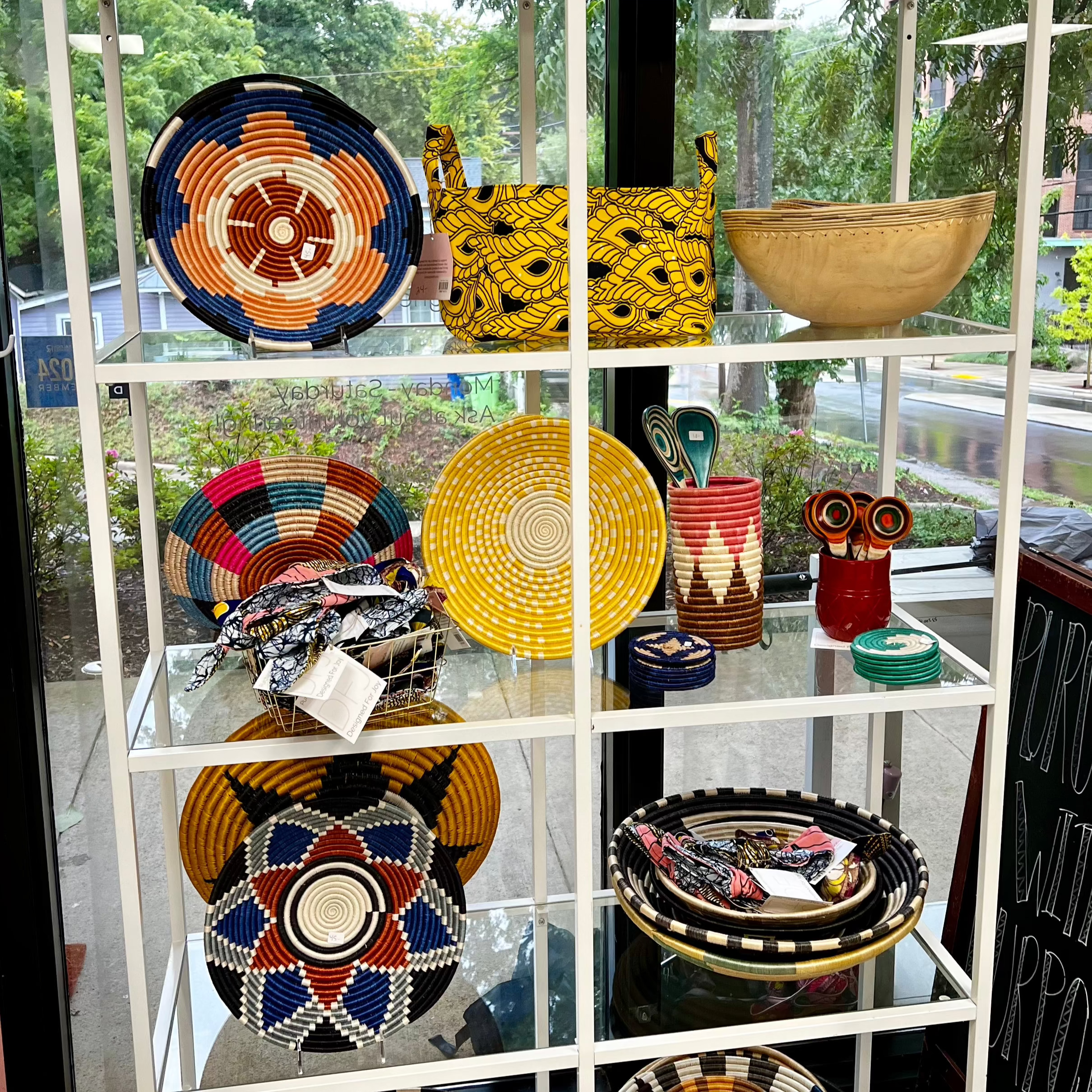 A display shelf of colorful Rwandan basket, bowls, utensils, and other merchandise
